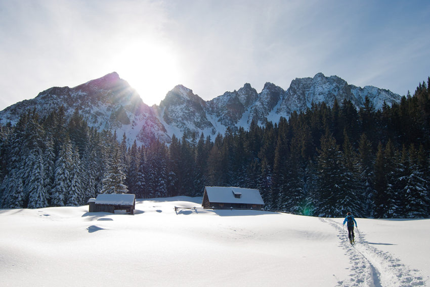 Mann unternimmt eine Skitour bei strahlendem Sonnenschein im Winter.