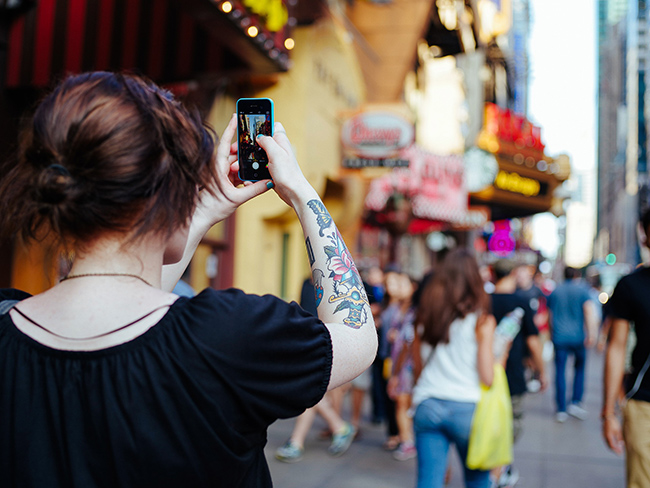 girl with smartphone takes a photo with the device.