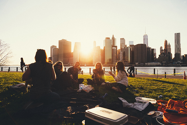 friends enjoy picnic in a parc. In the backgroud varios skyscrapers.