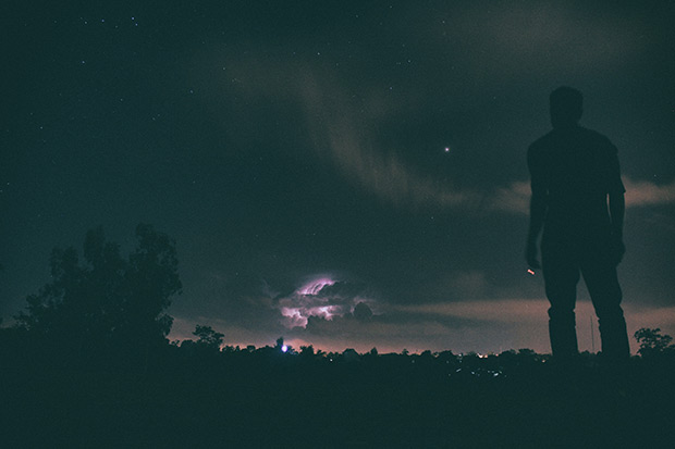 Ein Mann beobachtet ein Gewitter in der Nacht. © unsplash.com