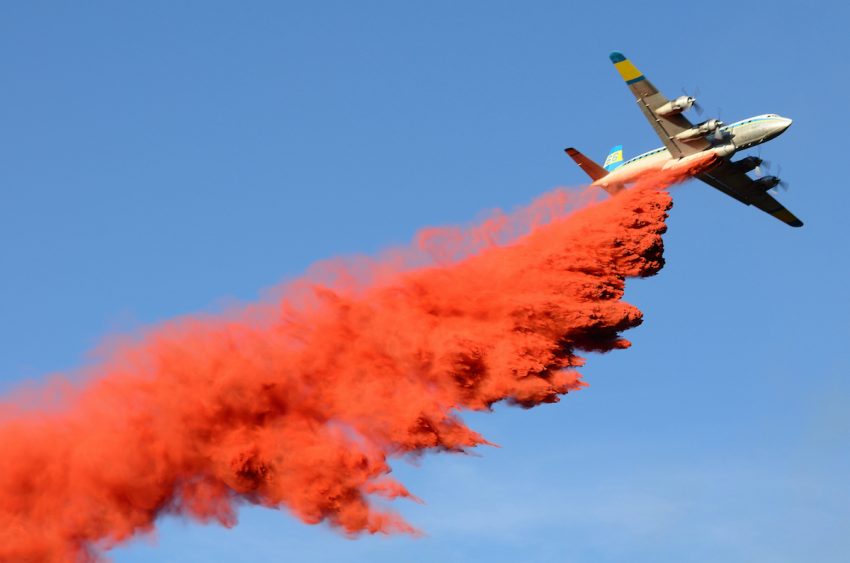 Löschflugzeug am Himmel mit roter Löschflüssigkeit (c) shutterstock.com/TFoxFoto